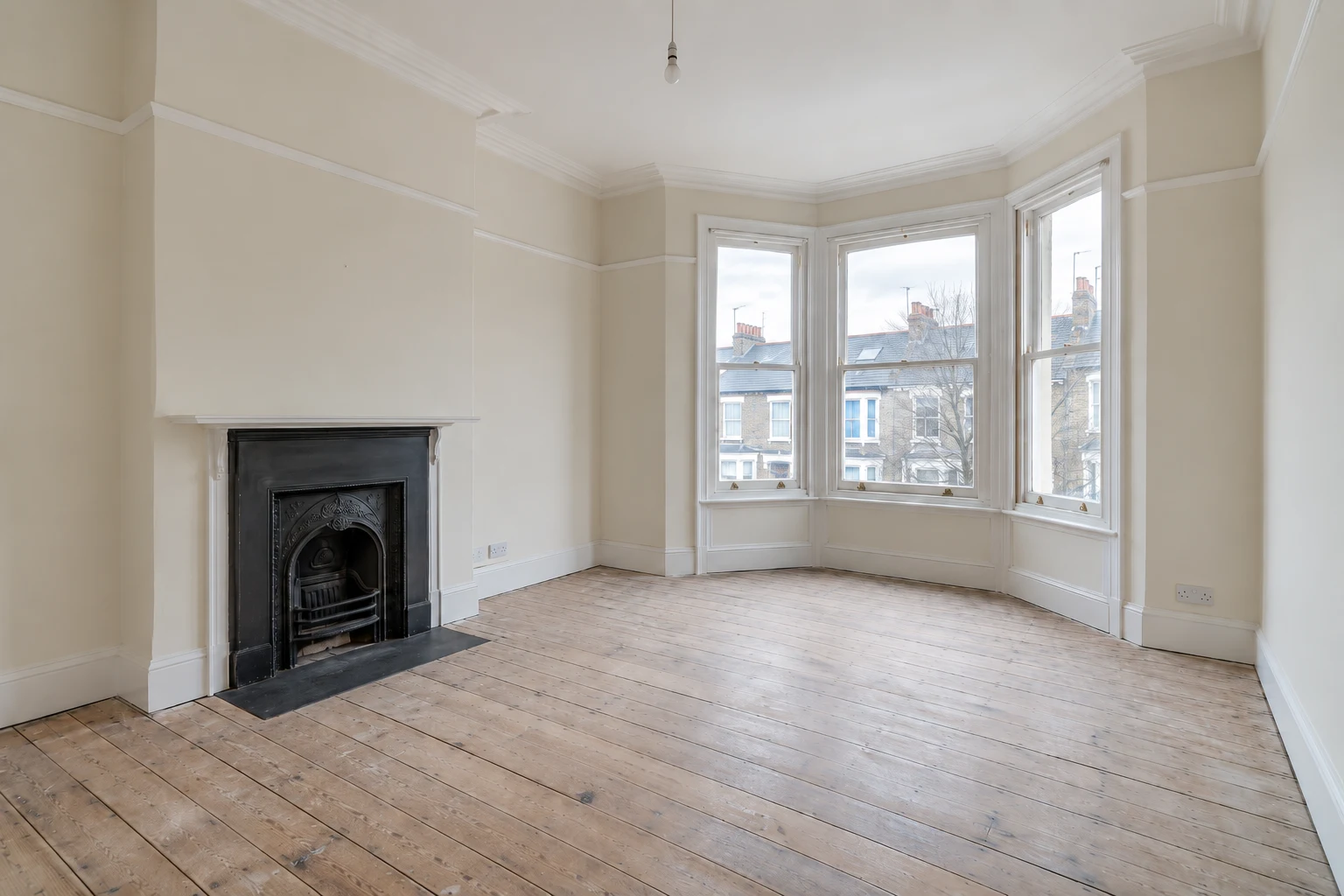 Original empty master bedroom with bay window and black fireplace